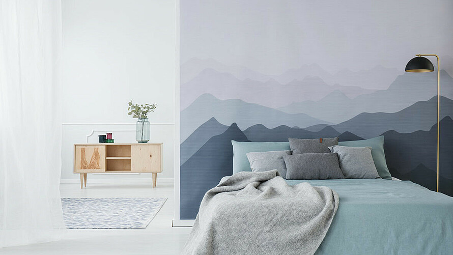 Bild zeigt Bett und bemalte Wand mit Bergmotiv