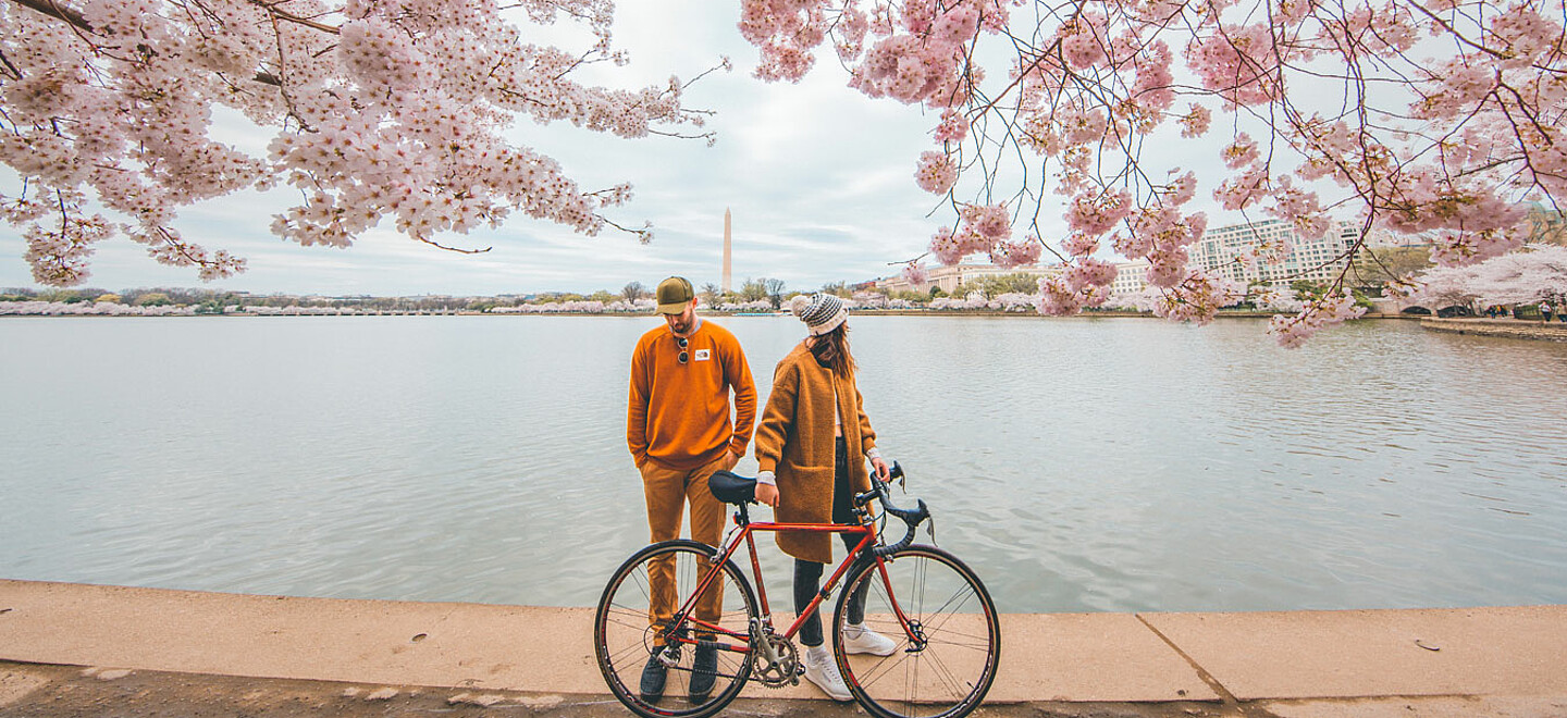 Mann und Frau stehen mit Fahrrad vor einem Fluss.
