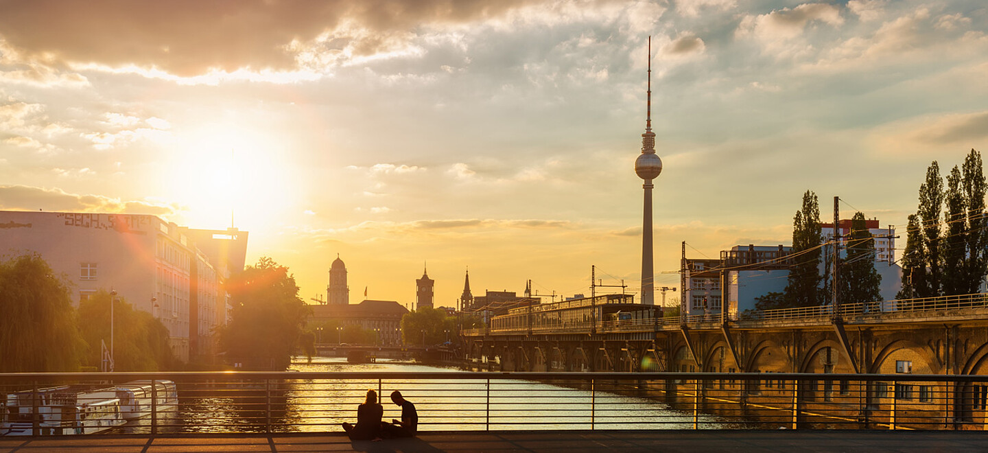 Die Sonne verschwindet im unteren Drittel des Bildes hinter der Berliner Skyline.