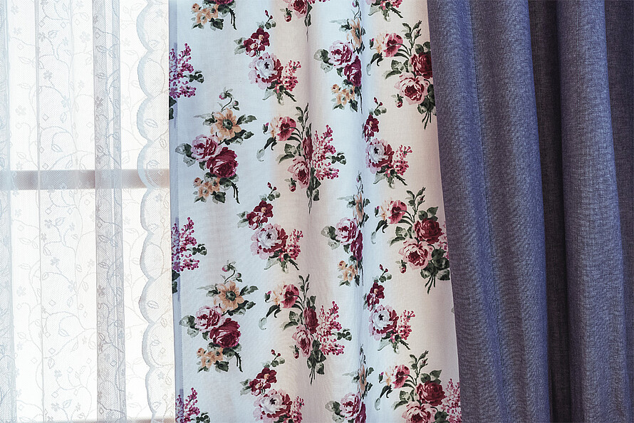 Ein bunter, tropischer Print auf in Falten liegendem Stoff eines Vorhangs.