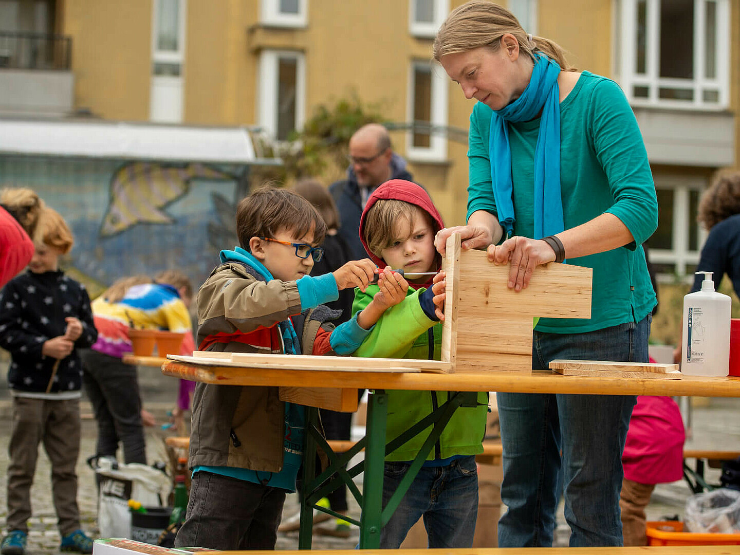 Frau hilft zwei Jungs etwas zusammenzubauen 