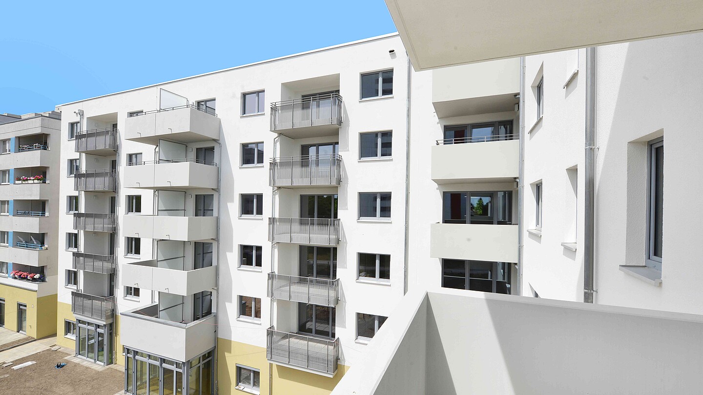 Blick vom Balkon eines weiß-gelben, mehrstöckigen Gebäudes mit Balkonen.