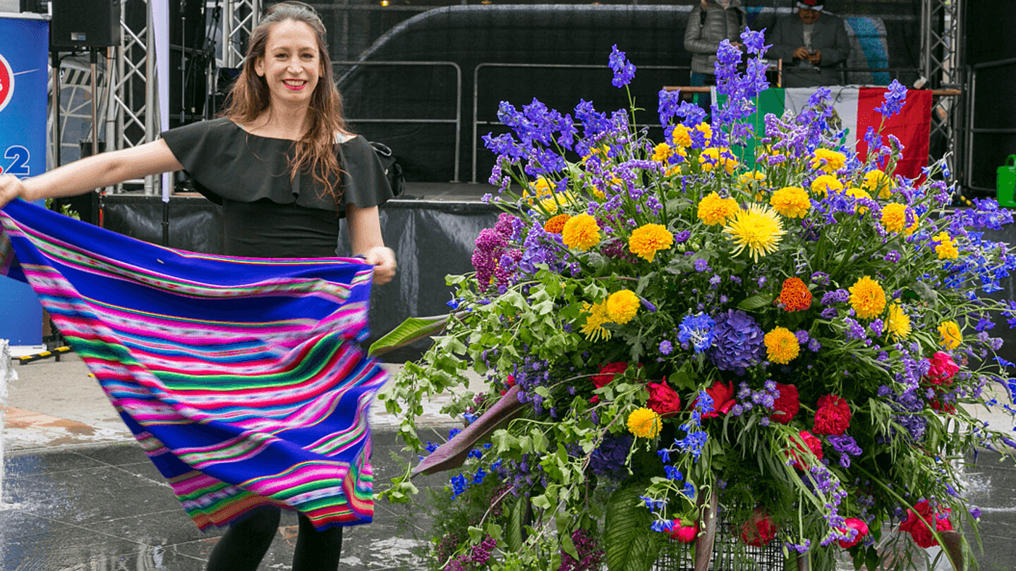 Frau steht neben großem Blumenkübel.