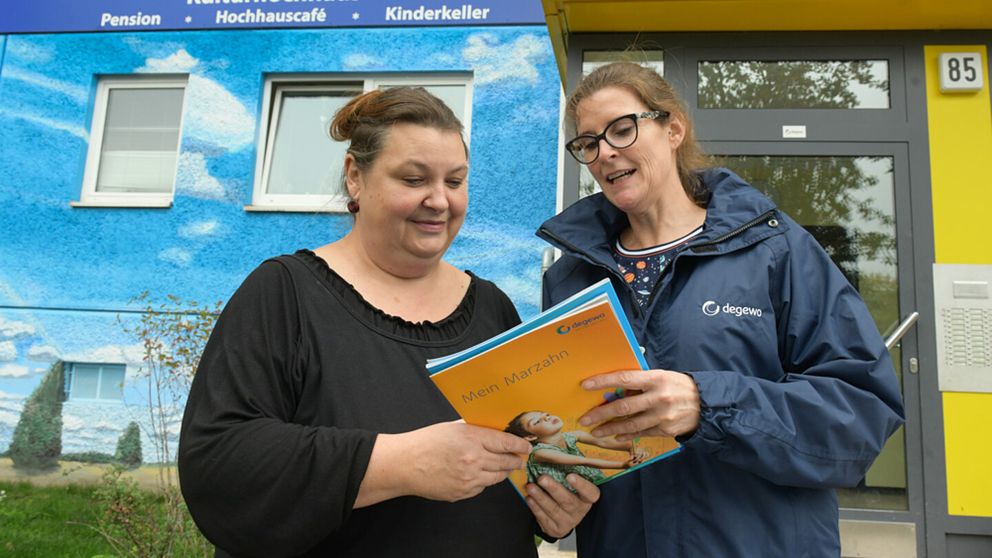 Zwei Frauen schauen auf Prospekte und diskutieren.