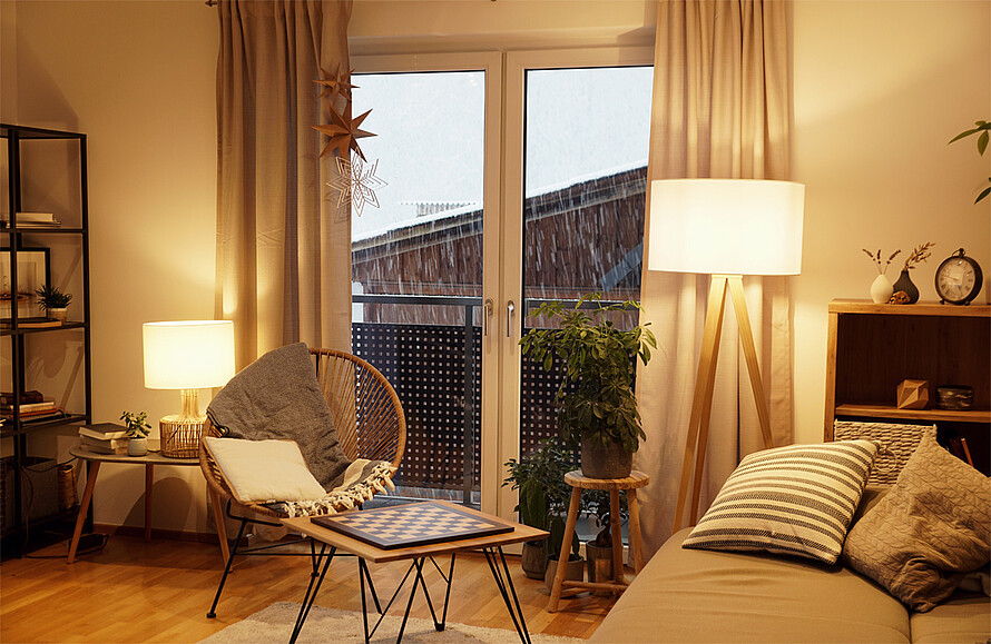 Ein Wohnzimmer mit zwei Lampen, einem Tisch und einer Couch.