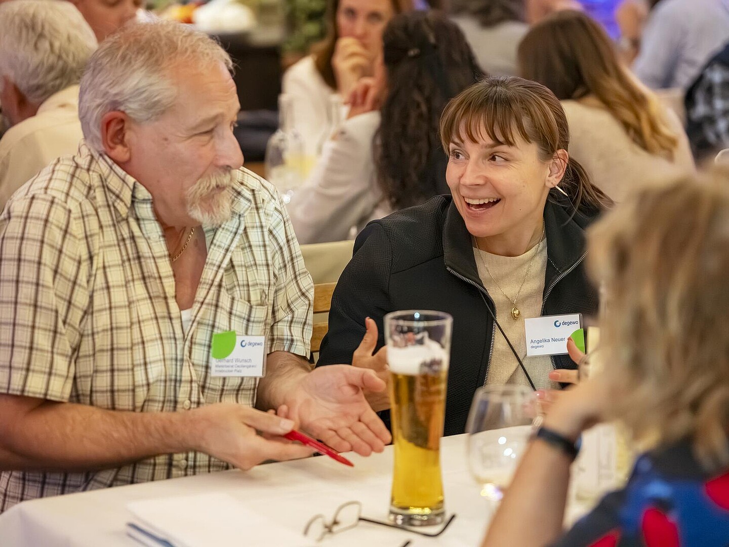 Zwei Gäste sitzen am Tisch, reden und lachen miteinander.