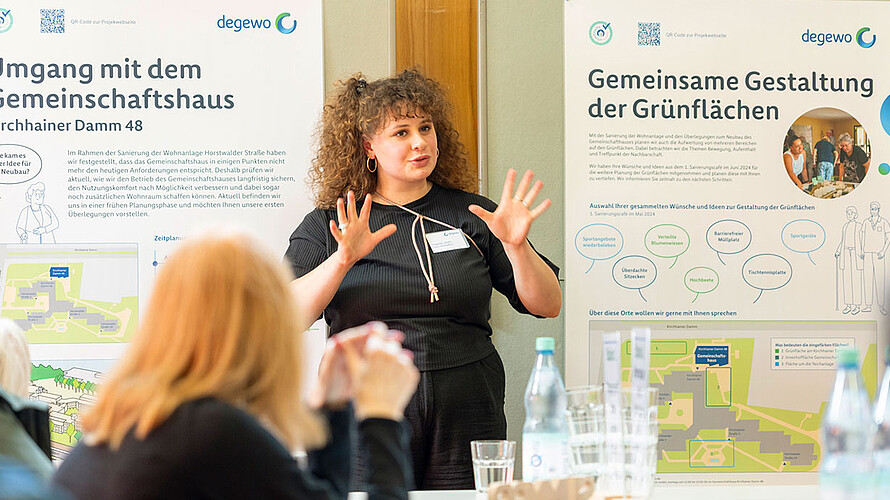 Eine Mitarbeiterin von degewo informiert auf einer Veranstaltung über die geplanten Maßnahmen. Mietende hören zu. 
