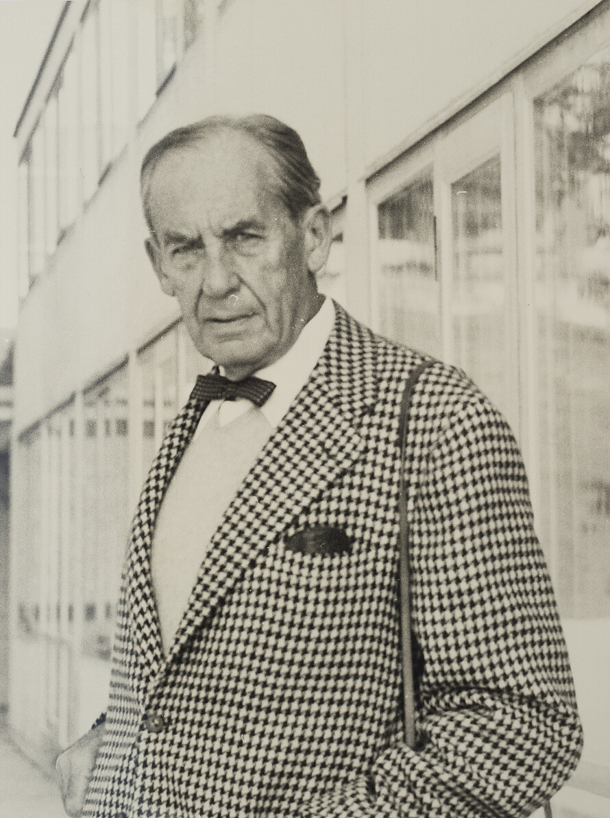 Walter Gropius im Portrait Eine Person blickt in die Kamera. Sie trägt ein kariertes Jacket und Fliege.