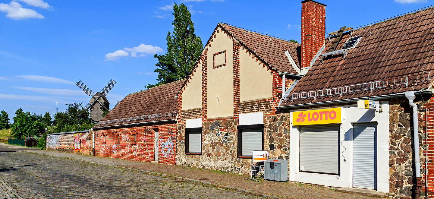 Mehrere Backsteinhäuser in Berlin-Marzahn. Dahinter gibt es eine Windmühle.