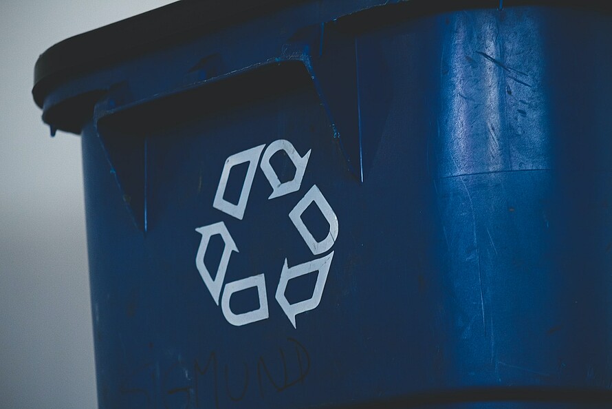 Eine blaue Mülltonne mit Recycling-Symbol auf der Vorderseite