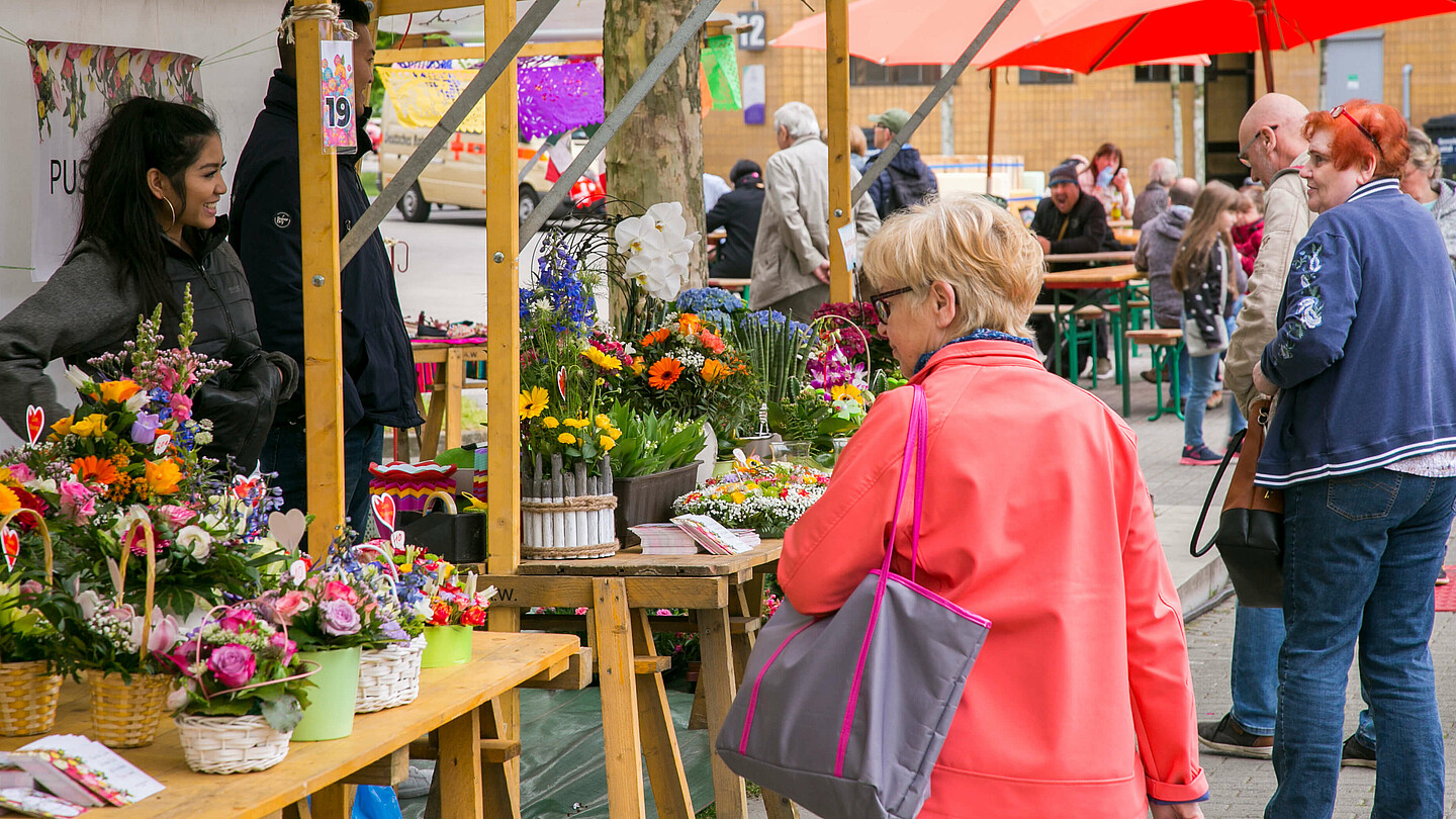 Frau steht vor einem Blumenstand.