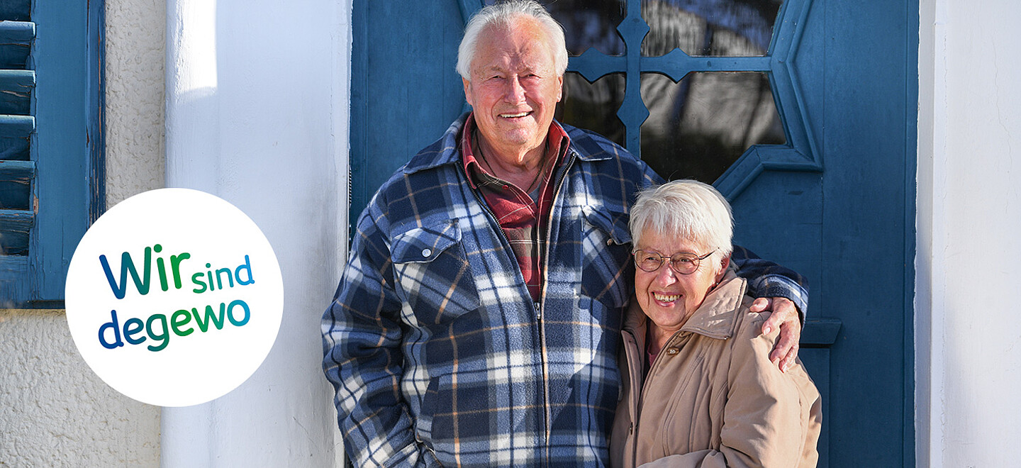 Klaus und Marion Liedtke vor der Eingangstür zu ihrem Haus in der Krugpfuhlsiedlung. Klaus Liedtke hat den Arm um die Schultern seiner Frau gelegt, die beiden lächeln in die Kamera.