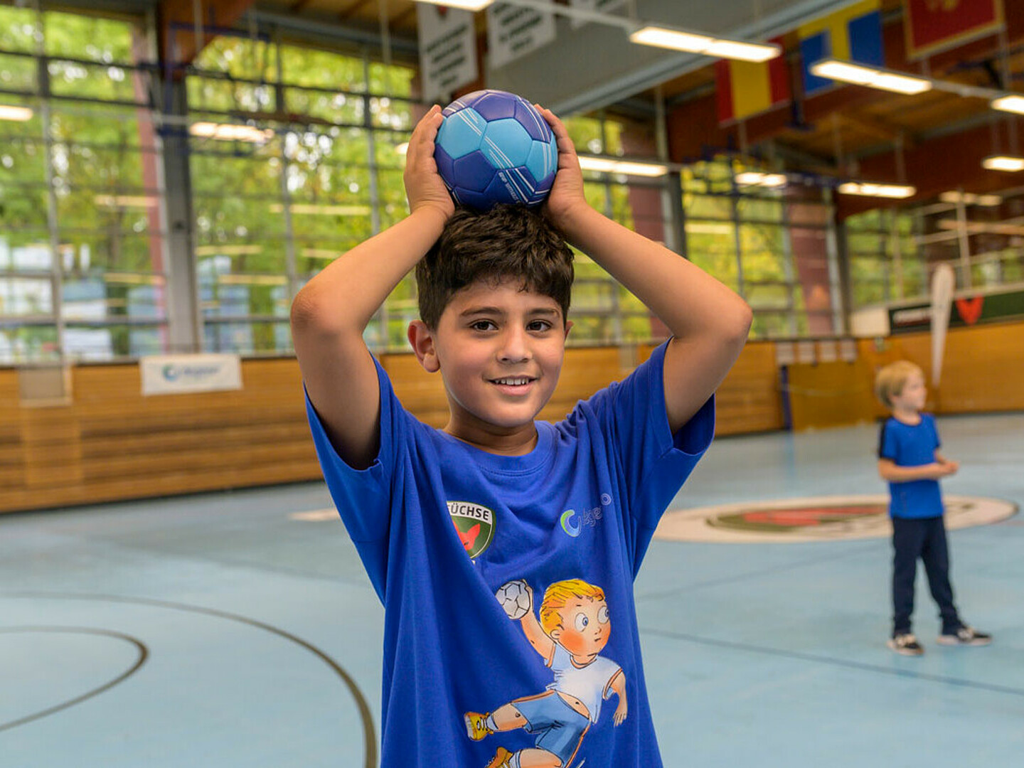 Ein Junge in blauer Sportkleidung von Füchse mit einem blauen Ball.