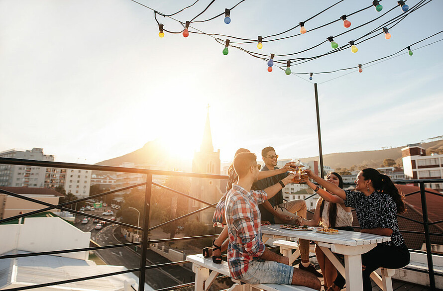 Eine Gruppe von Freunden trinkt Gläser auf dem schön dekorierten Dach eines Gebäudes.
