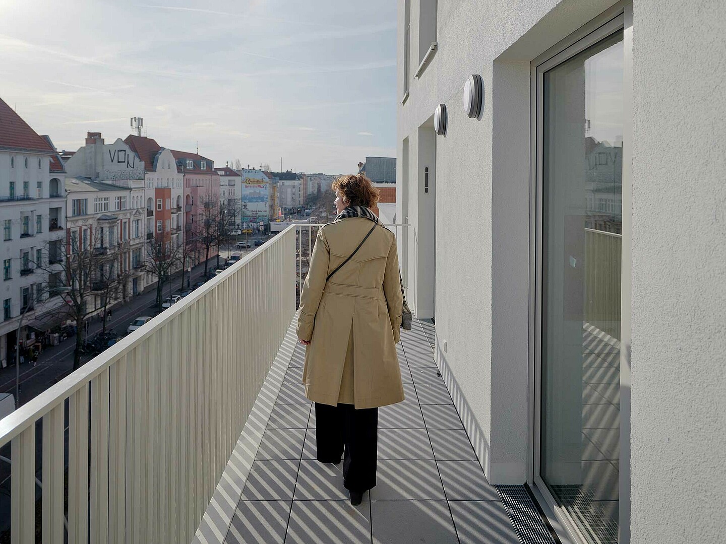 Anne Lampen läuft mit dem Rücken zur Kamera gewandt auf einem Balkon des Neubaus in der Gotenburger Straße. Sie schaut in die Ferne.