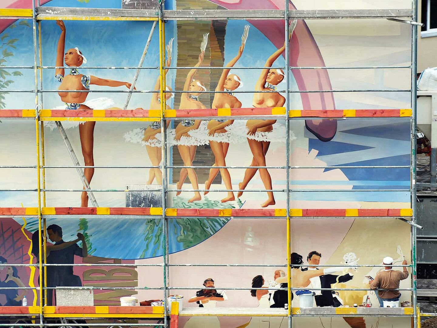 Das Bild zeigt ein bunten Gemälde an der Fassade eines Plattenbaus.
