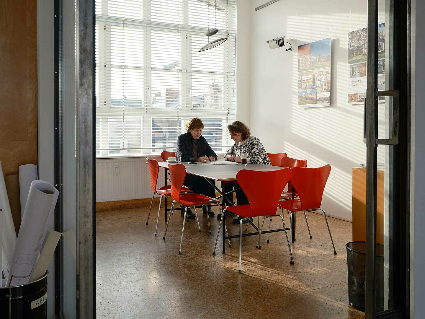 Anne Lampen und Susann Belitz sitzen an einem Tisch im Büro. Sie besprechen Entwürfe.