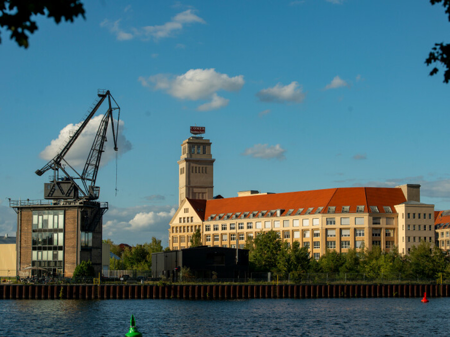 Blick über die Spree auf ein großes Wohnhaus und das Kranhaus Café.
