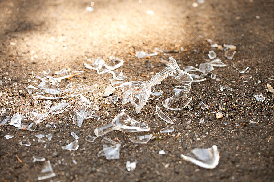 Zerbrochenes Glas auf einer Sandsteinboden.