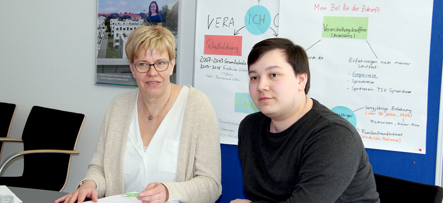 Eine Frau und ein junger Mann sitzen am Tisch.