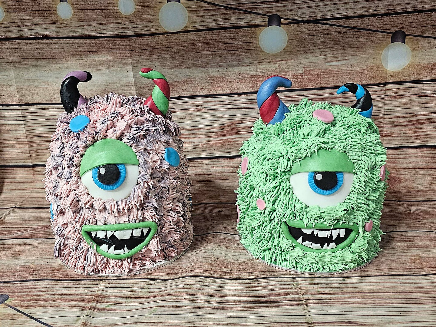 Zwei Torten in Monsteroptik. Links ein rosa Monster mit einem Auge und Hörnern, rechts ein grünes Monster mit einem Auge und Hörnern.
