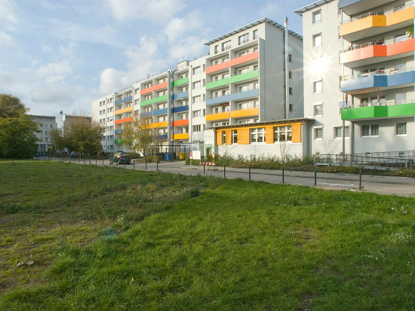 Ansicht eines bunt bemalten Plattenbaus mit Wiese davor.