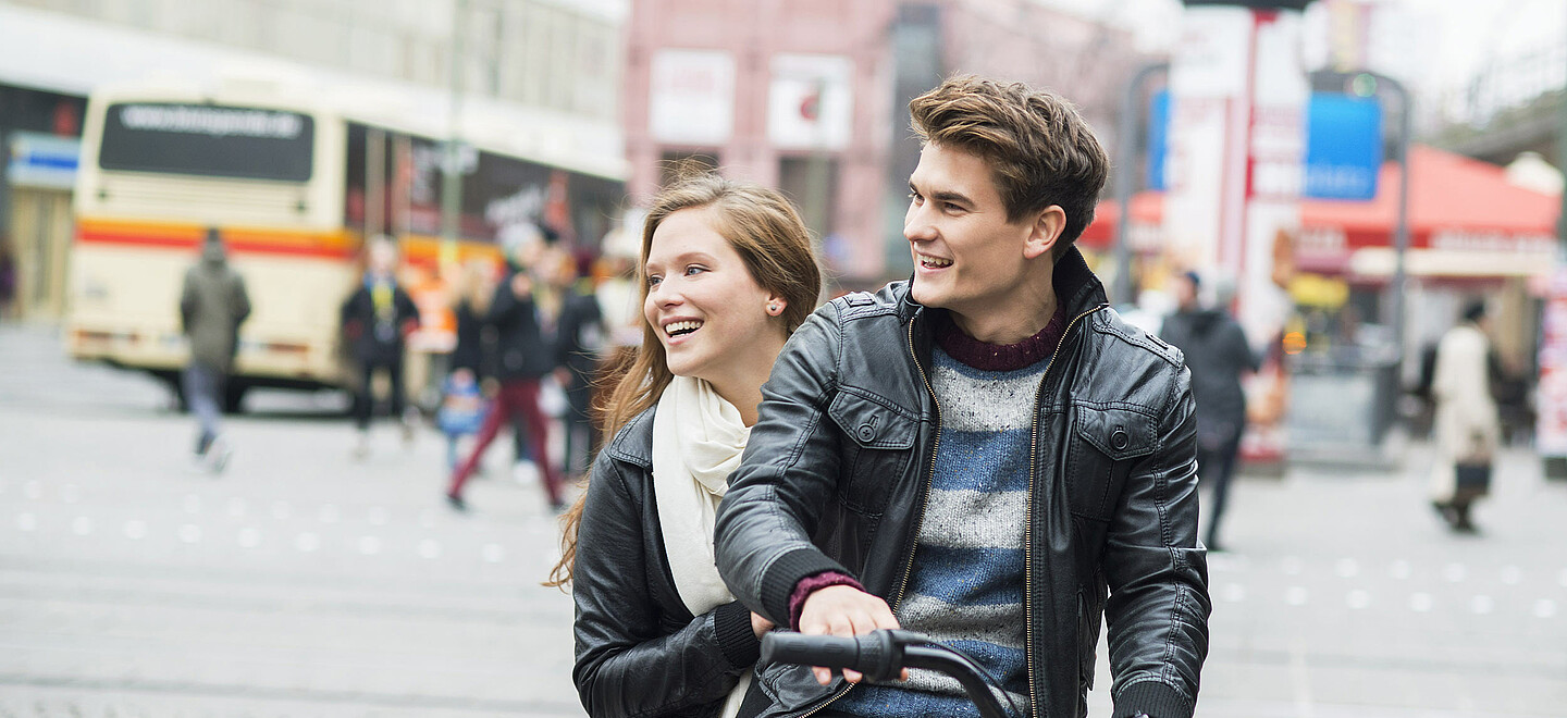 Ein junges Paar fährt auf dem Fahrrad durch die Stadt.