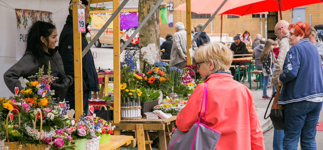 Seniorin läuft an Blumenständen vorbei.