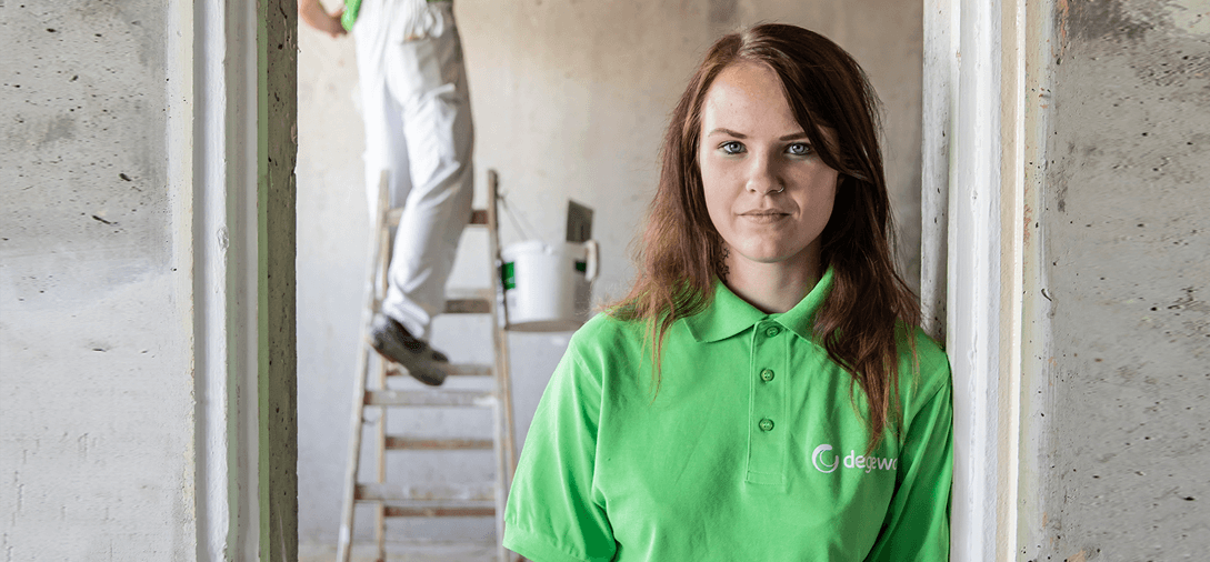 Handwerkerin der degewo, hinter Ihr eine Baustelle.