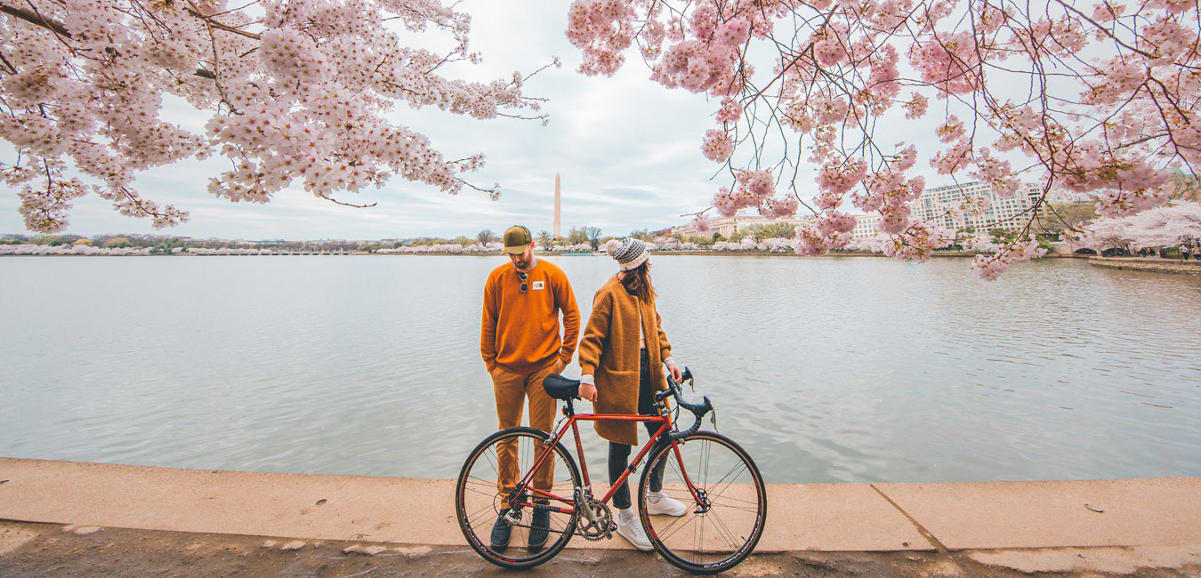 Mann und Frau stehen mit Fahrrad vor einem Fluss.