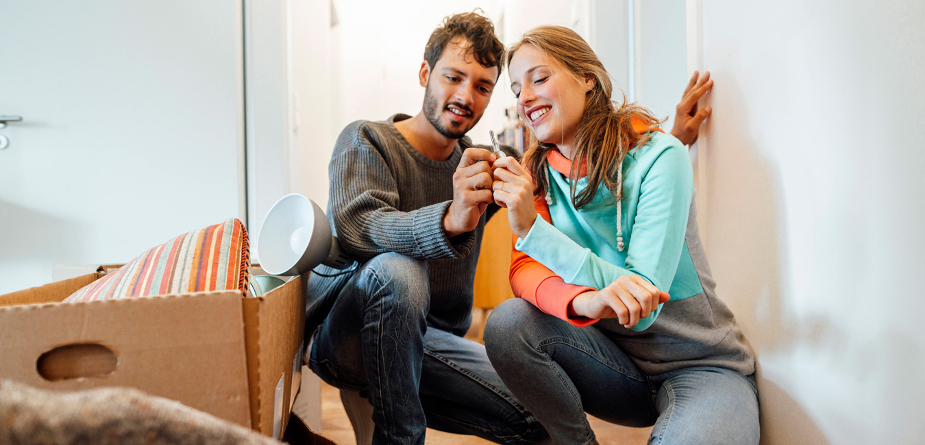 Ein glückliches junges Paar hält gemeinsam den Wohnungsschlüssel in den Händen