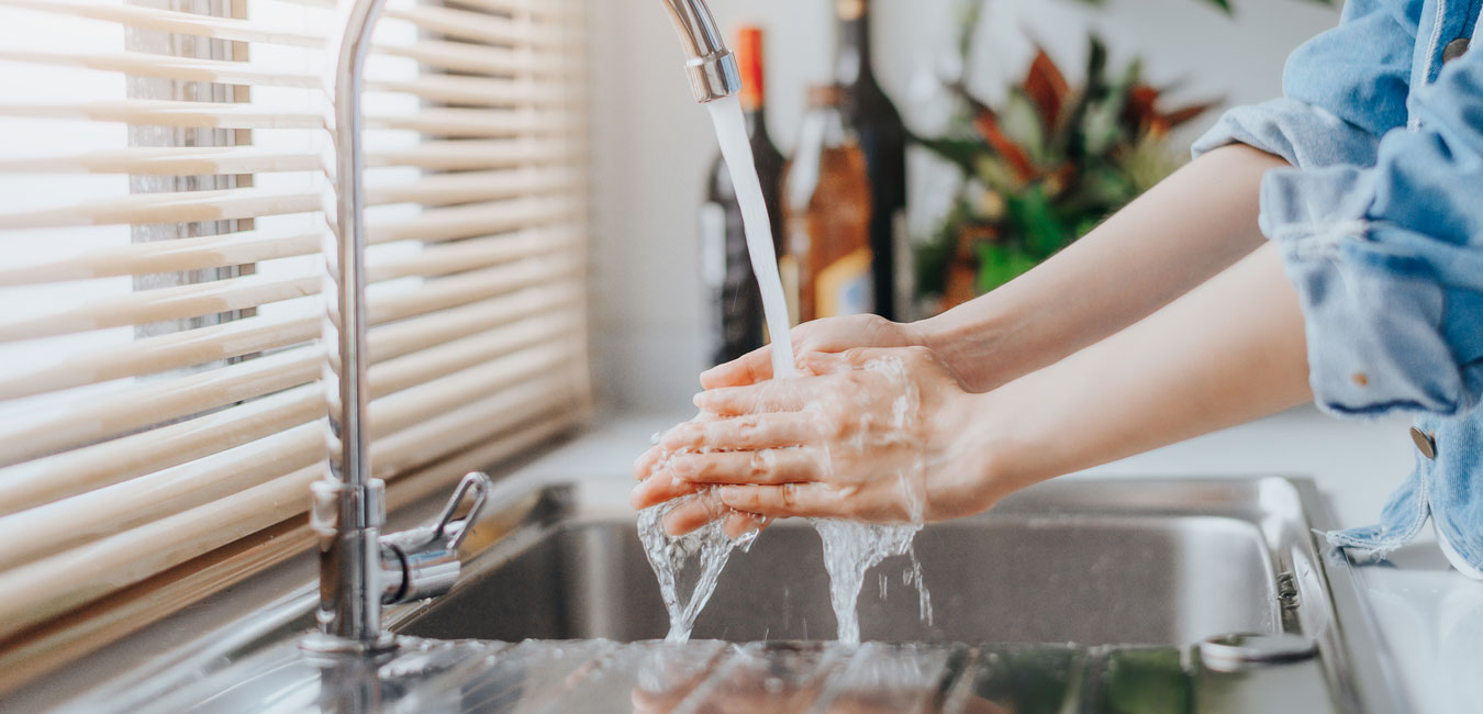 Person wäscht Hände unter laufendem Wasserhahn.