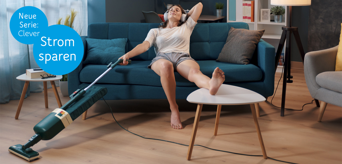 Eine Person sitzt im Wohnzimmer auf dem Sofa. Einen Fuß auf dem Couchtisch, hält sie in der rechten Hand einen Staubsauger und hört dabei über Kopfhörer Musik.