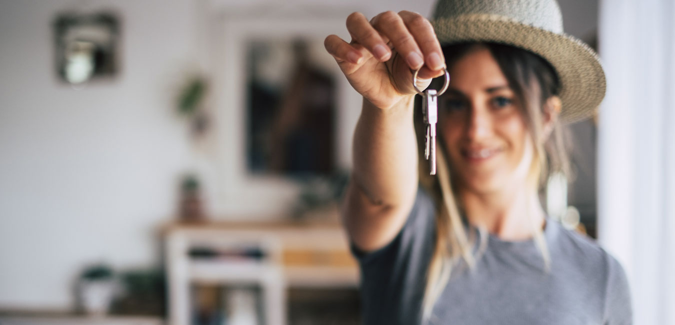 Eine Frau zeigt ihren Schlüssel der neuen Wohnung in die Kamera