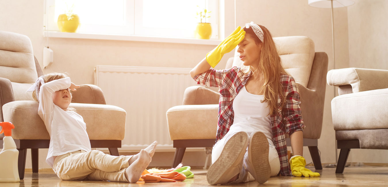 Mutter und Tochter sitzen nach dem Frühjahrsputz erschöpft am Boden.